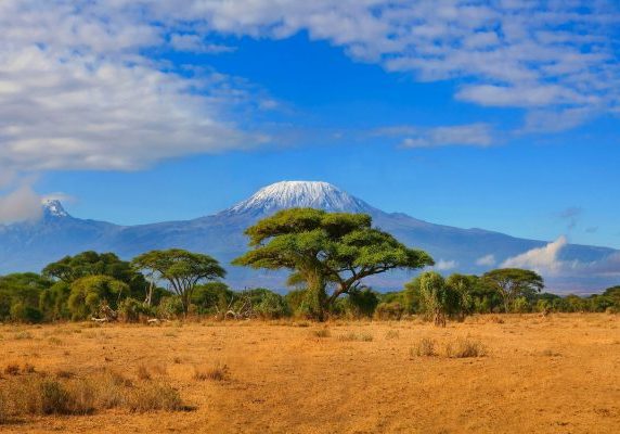 Kilimanjaro mountain Tanzania snow capped under cloudy blue skies captured whist on safari in Africa Kenya.